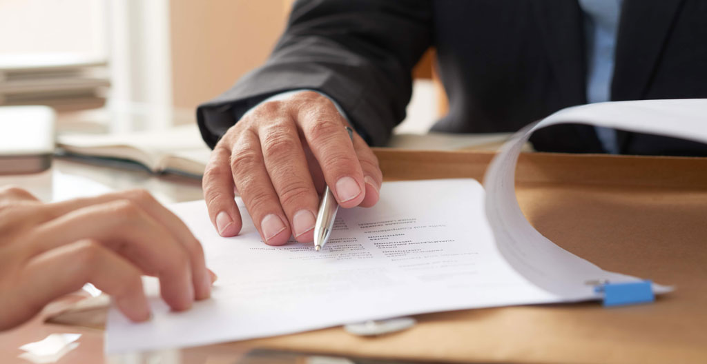 Des documents de copropriété étalés sur une table, une personne les consulte attentivement avant une décision d'achat